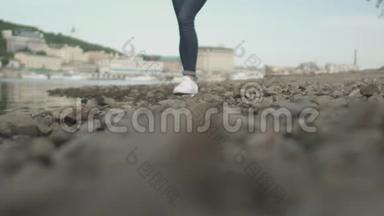 纤瘦的女士脚在河边的岩石上行走
